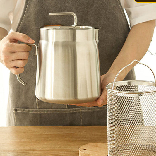 Person holding a stainless steel pot on a wooden surface with a metal mesh container in the foreground.