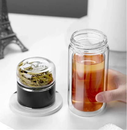 Tea Infuser Portable Bottle with tea leaves and a glass of iced tea on a white surface.