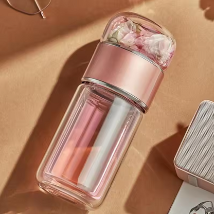 Pink Tea Infuser Portable Bottle with floral top on a beige surface